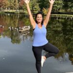 Paula in tree pose by a pond.