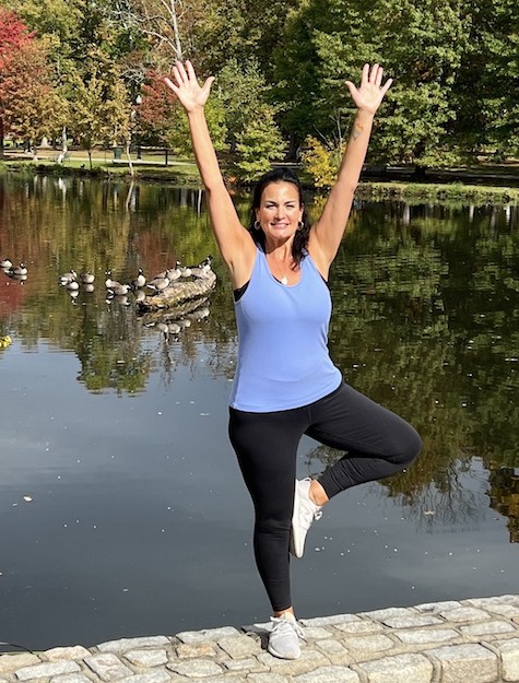 Paula in tree pose by a pond.